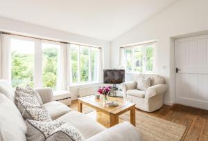 a living room with white furniture and windows at Little Winters Cottage in Lyme Regis