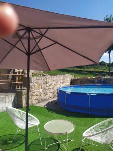 a large umbrella and two chairs and a pool at REMANSO DE TRASFONTAO "Casa do Campo" in Silleda
