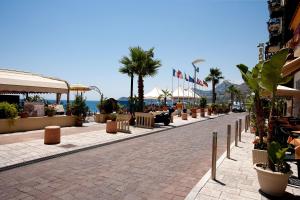 a cobblestone street with cafes and palm trees at Polifemo in Letojanni