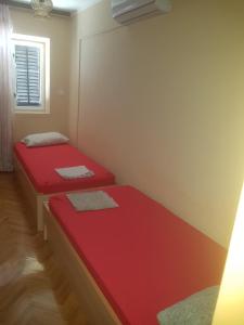two beds in a room with red sheets at Apartment 51 in Gornji Karin