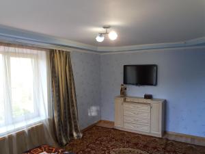 um quarto com uma televisão numa parede com uma janela em Татьянин двор em Kamianets-Podilskyi