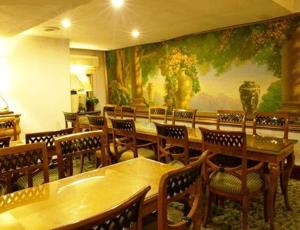 a restaurant with tables and chairs and a large painting on the wall at Diamond City Hotel SHA Certified in Bangkok