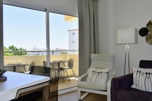 ein Wohnzimmer mit einem Sofa und einem Stuhl sowie einem Balkon in der Unterkunft Playa Flores Deluxe - Vistas a la piscina in Torremolinos