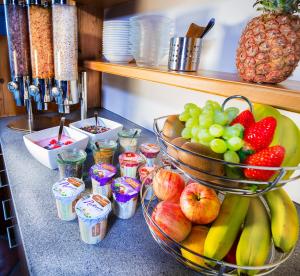 a counter topped with bowls of fruit and cups at Hotel Oberland in Triesenberg