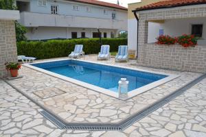 a swimming pool with two chairs and a water bottle at ARA-ZAROK in Baška