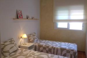 ein Schlafzimmer mit einem Bett, einer Lampe und einem Fenster in der Unterkunft Tresmall in Les Cases d'Alcanar