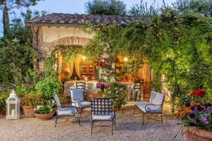 a patio with chairs and an arch with flowers at Villa Cicolina in Montepulciano