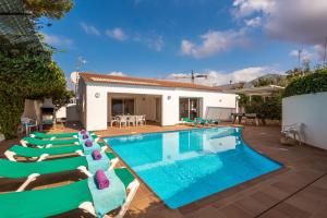 a pool with lounge chairs and a house at Villa Menorca Raquel by Mauter Villas in Cala en Bosc