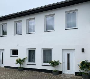 a white building with windows and potted plants at Ferienwohnung Felix in Schleswig