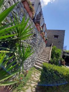 pared de piedra con escaleras junto a un edificio en Agriturismo Orrido di Pino, en Agerola