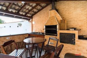 a kitchen with a wooden table and a fireplace at Casa na Praia Grande com piscina, churrasqueira e ar condicionado - 04 dormitórios in Ubatuba