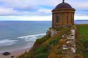 a building on a cliff next to the ocean at Luxury apartment in the heart of Portrush Main St in Portrush