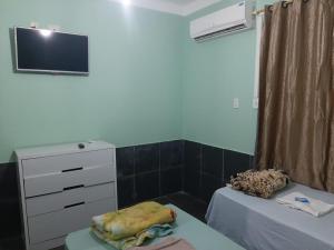 a room with two beds and a dresser and a tv at Pousada Alojamento Fragoso in Itaguaí