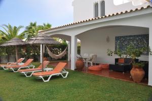 um grupo de cadeiras e guarda-sóis num pátio em Luxury 3 bedroom Villa with Private Pool em Cabanas de Tavira