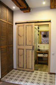 ein Badezimmer mit einer Holztür und einem Waschbecken in der Unterkunft Apartamenty Luizjana in Toruń