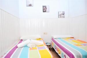 マラガにあるApartamento Veronicaの白い部屋のベッド2台 カラフルなシーツ付