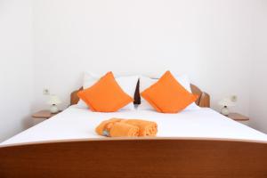 a bed with orange pillows and a towel on it at Apartments Marin in Bol