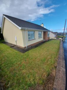 a house with a grass yard in front of it at HOMELY YELLOW BUNGALOW -Articlave-near Castlerock in Castlerock