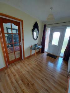 HOMELY YELLOW BUNGALOW -Articlave-near Castlerock في كاسيل روك: غرفة معيشة مع أرضية خشبية وباب