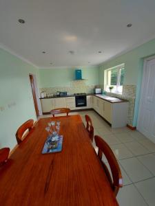 a dining room table with chairs and a kitchen at HOMELY YELLOW BUNGALOW -Articlave-near Castlerock in Castlerock