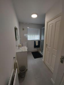 a white bathroom with a sink and a shower at HOMELY YELLOW BUNGALOW -Articlave-near Castlerock in Castlerock