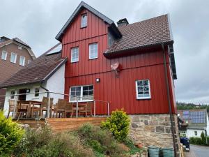 a red house with chairs and tables in front of it at Kleines Berghaus in Braunlage