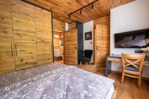 1 dormitorio con paredes de madera, 1 cama y escritorio en Nad Stawami, en Kartuzy