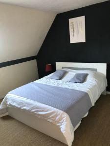 a bedroom with a large white bed with a black wall at Chambres d'hôte du Domaine de la Reine Blanche in Criquetot-sur-Longueville