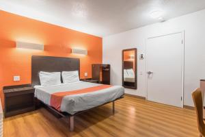 um quarto com uma cama com uma parede laranja em Motel 6 Bakersfield em Bakersfield
