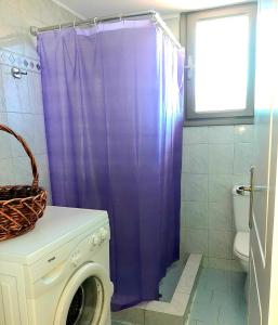 Una cortina de ducha morada en un baño con lavadora. en Villa Konari, en Tolo