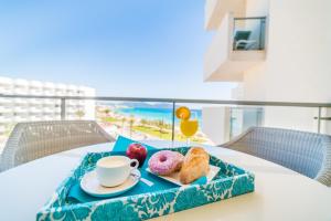 a tray of donuts and a cup of coffee on a table at Sa Maniga 5E in Cala Millor