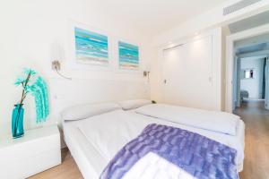 a white bedroom with a white bed and a purple blanket at Sa Maniga 5E in Cala Millor