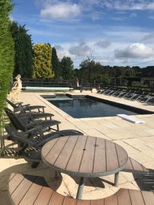 a patio with a table and chairs next to a pool at Chambres d'hôte du Domaine de la Reine Blanche in Criquetot-sur-Longueville