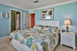 ein Schlafzimmer mit einem Bett mit Blumenbettdecke und einem Nachttisch in der Unterkunft Sand Blast - Lovely Beachfront Home With Tons Of Space! in Panama City Beach