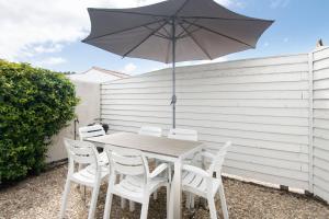 a wooden table with white chairs and an umbrella at Maison Campanule in La Flotte +2 photos