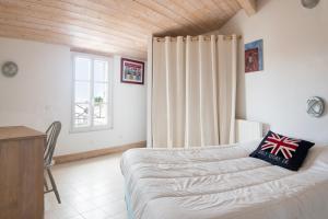 a bedroom with a bed and a desk and a window at Maison Campanule in La Flotte