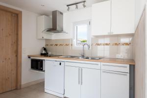 cocina con armarios blancos, fregadero y ventana en Maison Campanule en La Flotte