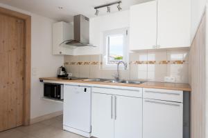a kitchen with white cabinets and a sink and a window at Maison Campanule in La Flotte