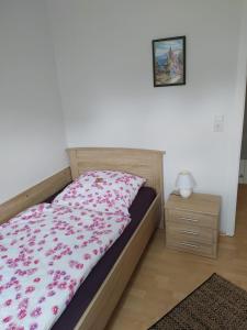 um quarto com uma cama com uma colcha floral e uma mesa de cabeceira em Ferienhaus Middenmank em Emden