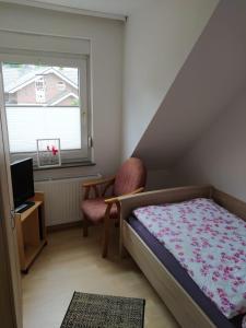 a bedroom with a bed and a chair and a window at Ferienhaus Middenmank in Emden