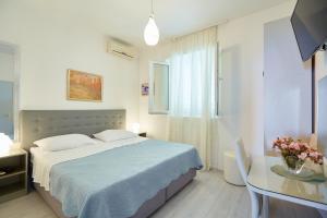 a bedroom with a bed and a desk and a table with flowers at Apartment Rose Garden in Dubrovnik