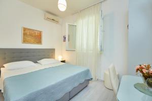 a white bedroom with a blue bed and a table at Apartment Rose Garden in Dubrovnik