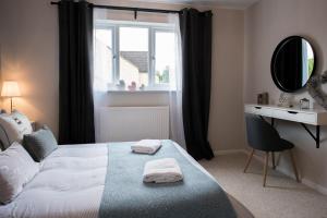 a bedroom with a bed and a mirror and a window at Green Lake House in Bourton on the Water