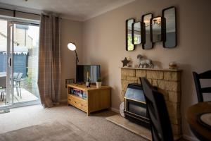 a living room with a tv and a fireplace at Green Lake House in Bourton on the Water