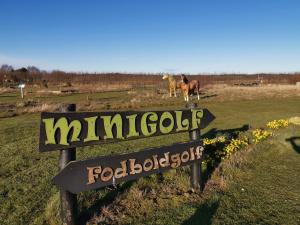 una señal en un campo con un caballo en el fondo en Vestbjerg Apartments, en Vestbjerg