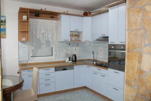 uma cozinha com armários brancos e uma mesa em Apartments Grmaca em Trogir