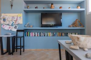 a room with a blue wall with a tv and a desk at Pelagos Apartments in Skala