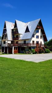 een groot huis met een gambrel dak met een groen gazon bij Antonówka in Trybsz