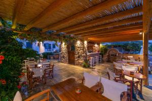 a patio with tables and chairs under a wooden pergola at Almyra Seaside Suites in Platis Gialos