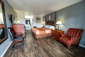 um quarto de hotel com uma cama e uma cadeira em American Inn & Suites Russellville em Russellville